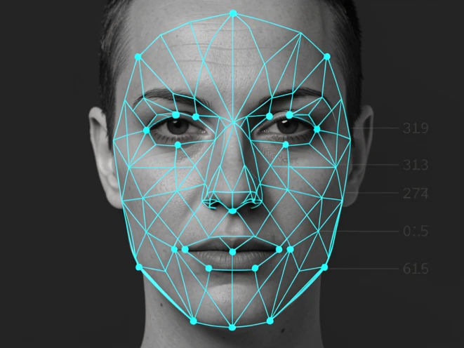 A front-facing human face overlaid with a bright cyan wireframe mesh marking facial landmarks, small dots pinned to eye corners, nose tip, mouth corners, and along the jawline, thin lines connecting them into a triangulated map. The face sits centered against a dark charcoal background, with faint coordinate numbers floating beside three of the landmark dots. Crisp, even light from directly in front renders the mesh sharp and the skin a neutral gray. Technical, diagnostic atmosphere.