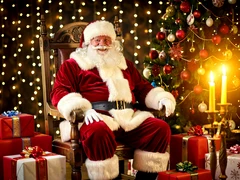 A cheerful Santa Claus figure in a classic red velvet suit trimmed with white fur sitting in a large wooden chair surrounded by wrapped gift boxes and a decorated Christmas tree, warm golden candlelight glowing from the right side, soft bokeh background of twinkling fairy lights, festive and cozy holiday atmosphere with rich seasonal colors.